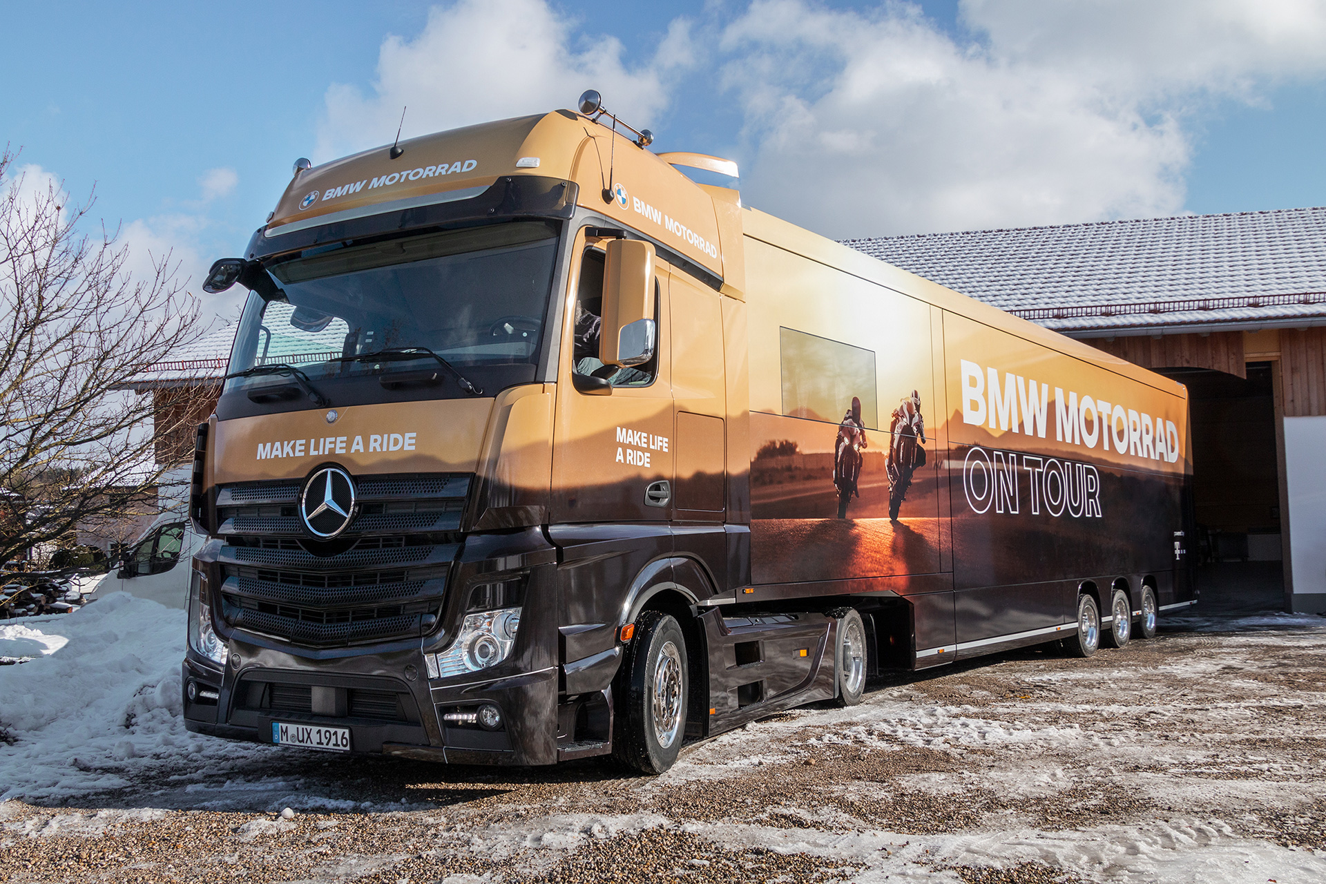 BMW Motorrad Roadshow Truck – Schrägansicht vorne mit „BMW Motorrad On Tour" Beklebung und goldenem Sonnenuntergang-Motiv, Gestaltung: ZP Medienwerk